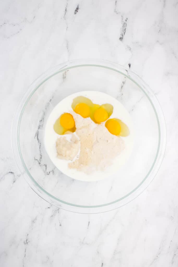 glass bowl with ingredients for sourdough brioche added but not mixed