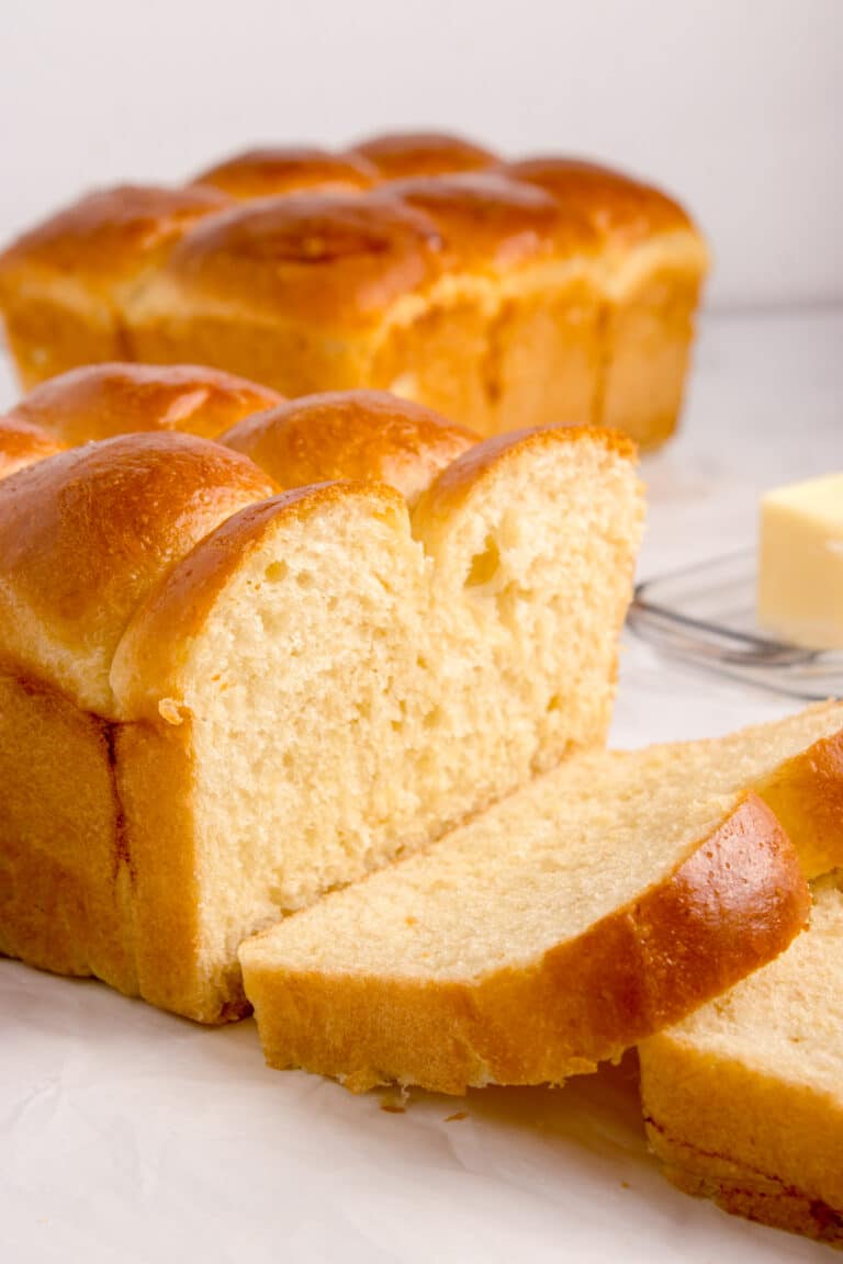 two loaves of sourdough brioche on counter with one loaf sliced to show inside texture