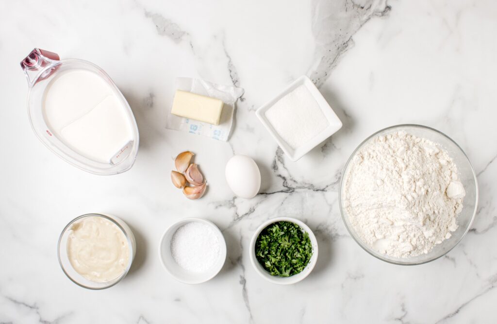 ingredients for sourdough garlic knots in glass bowls on marble counter