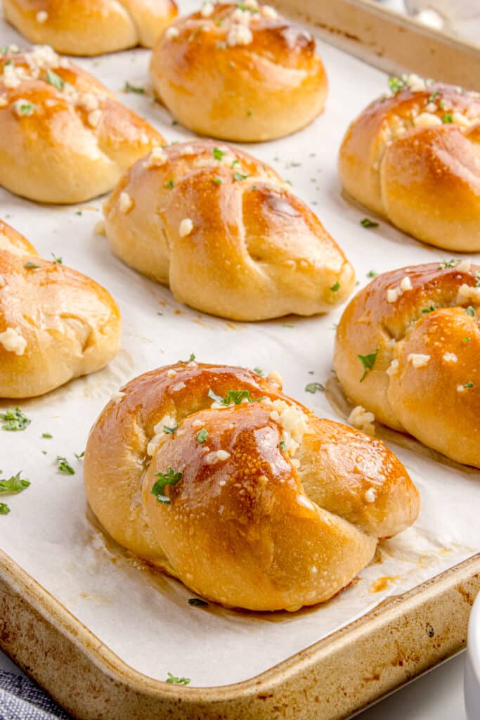 sourdough garlic knots on baking tray with garlic butter brushed on top