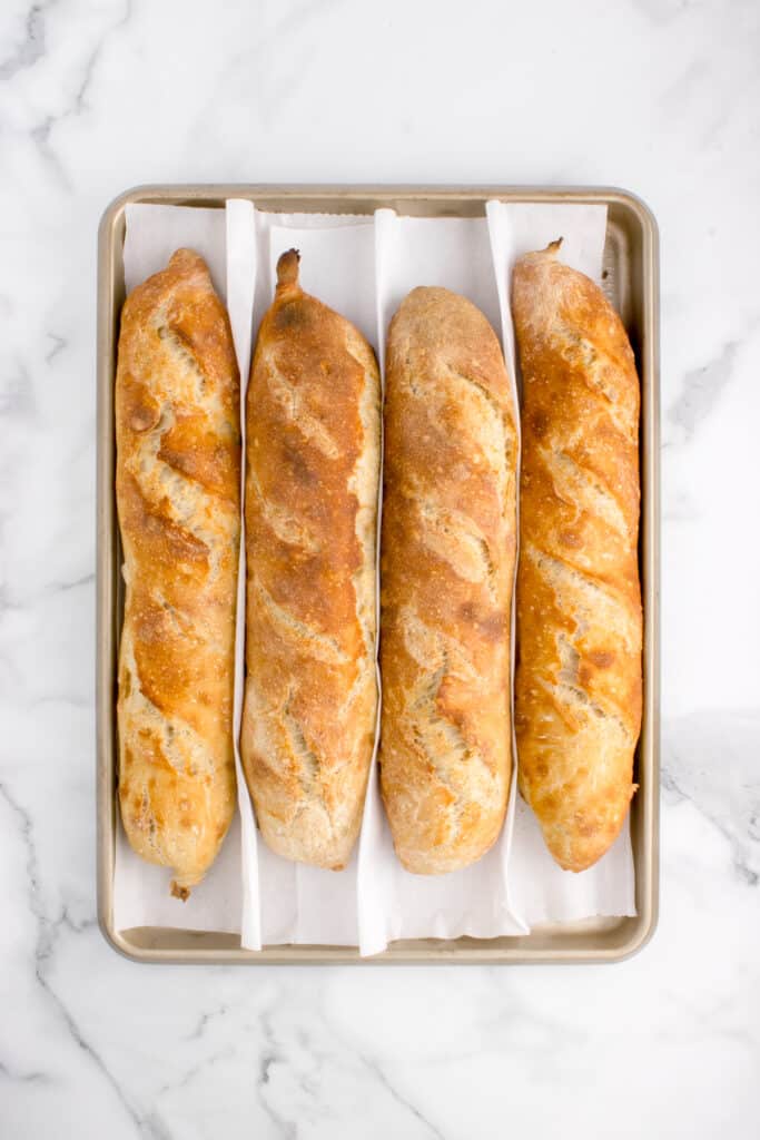 freshly baked sourdough baguette on baking pan