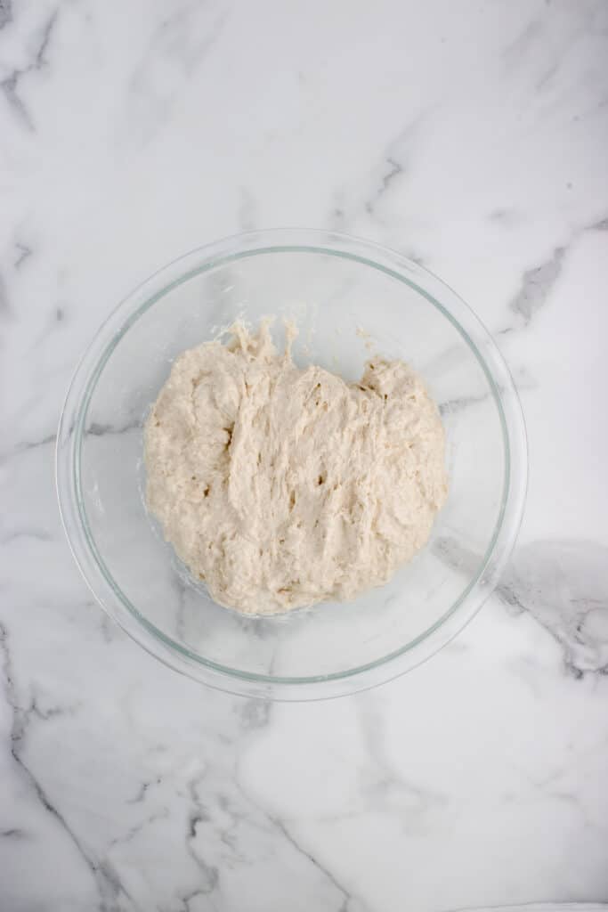 sourdough baguette dough in glass bowl after stretch and fold