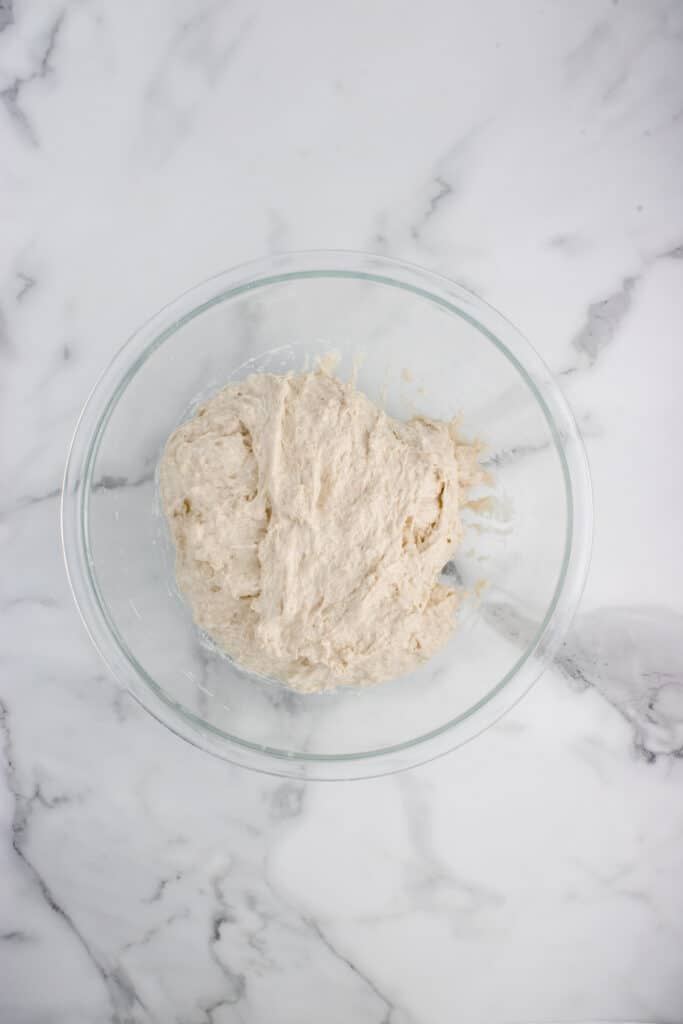 sourdough baguette dough in glass bowl after stretch and fold