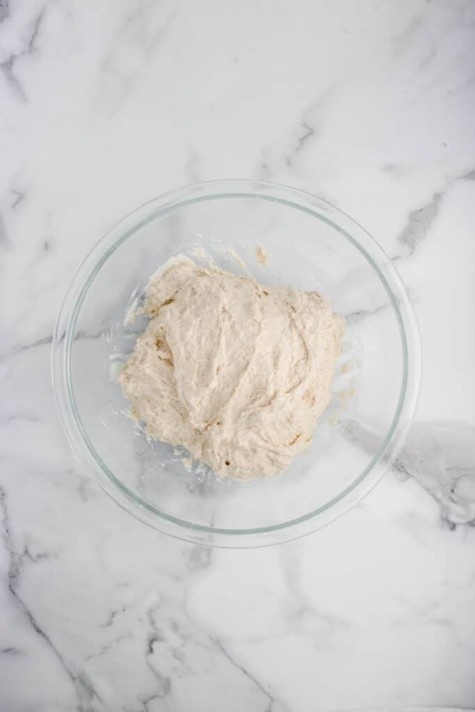sourdough baguette dough in glass bowl after stretch and fold