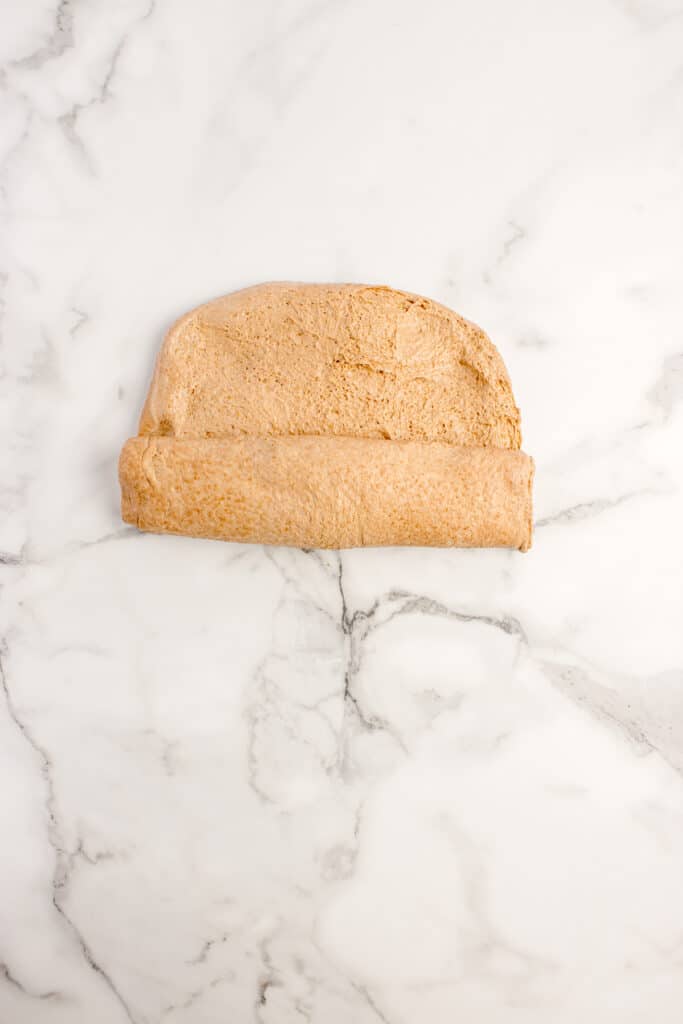 small rectangle of dough being rolled into log