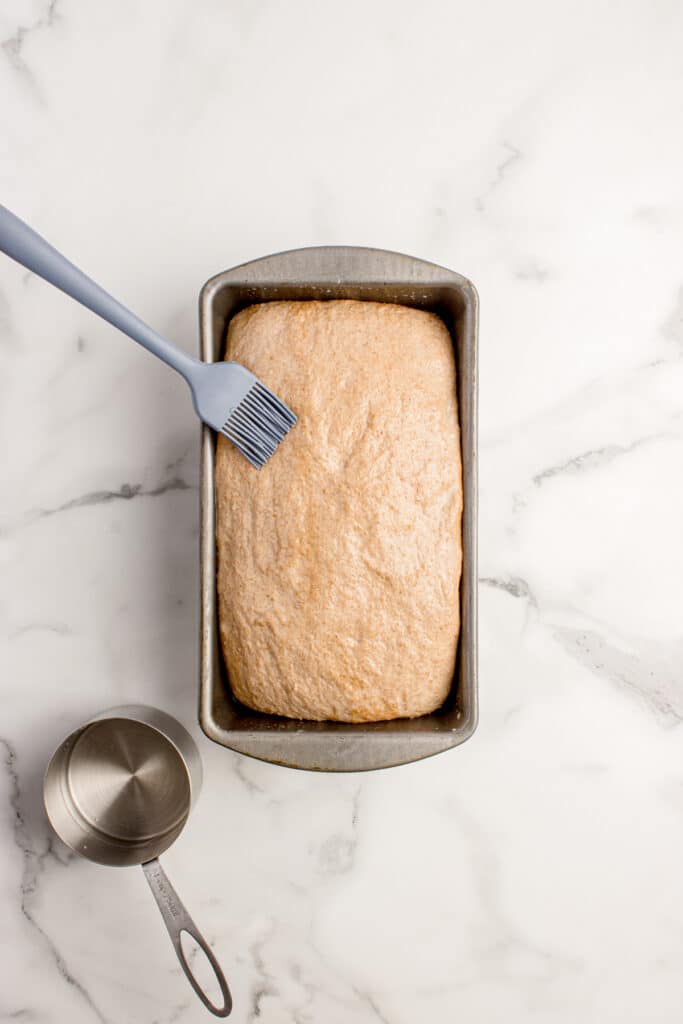 pastry brush adding water to loaf to stick on oats