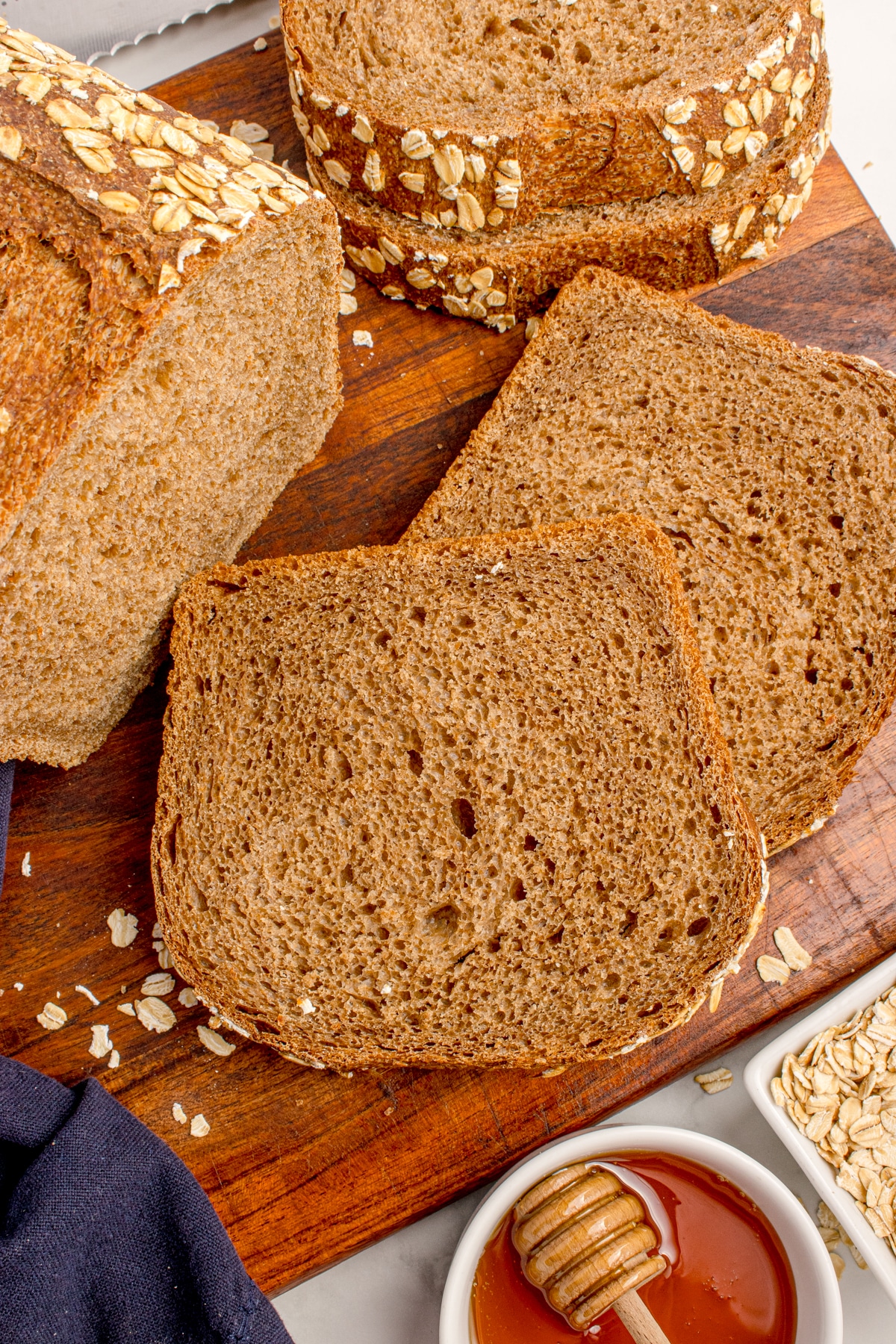 sourdough brown bread slices on board next to loaf