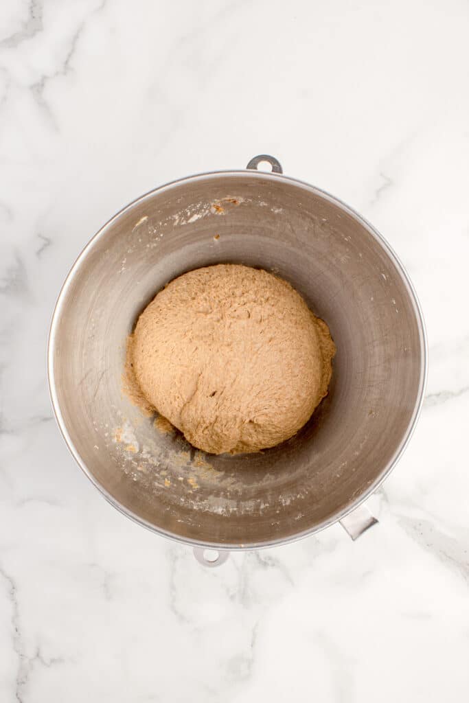 mixed dough for sourdough brown bread in metal mixing bowl