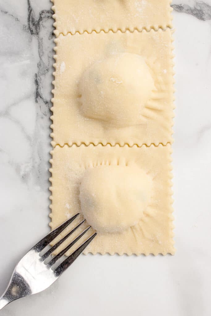 fork pressing rides into cheese ravioli square