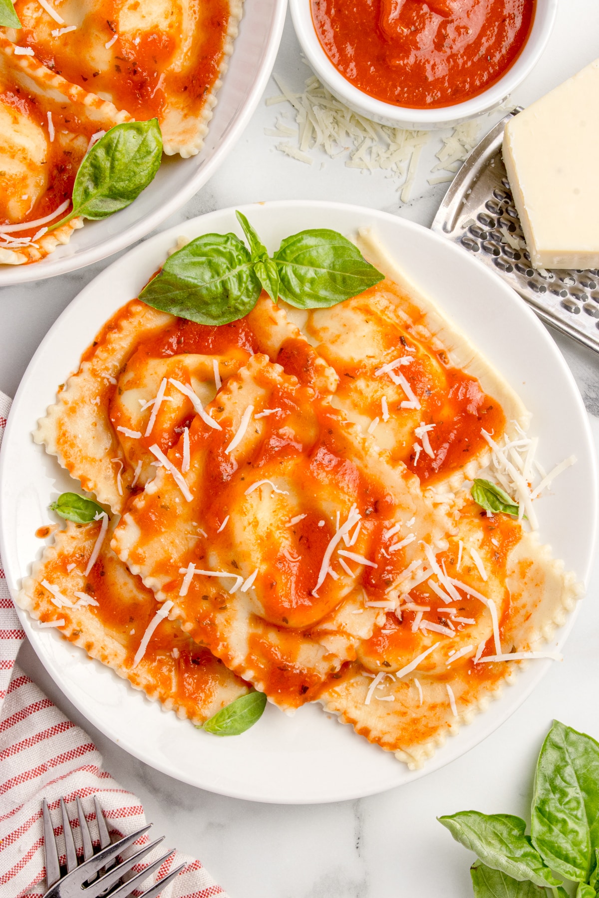 overhead view of white plate filled with sourdough cheese ravioli with sauce, cheese, and basil