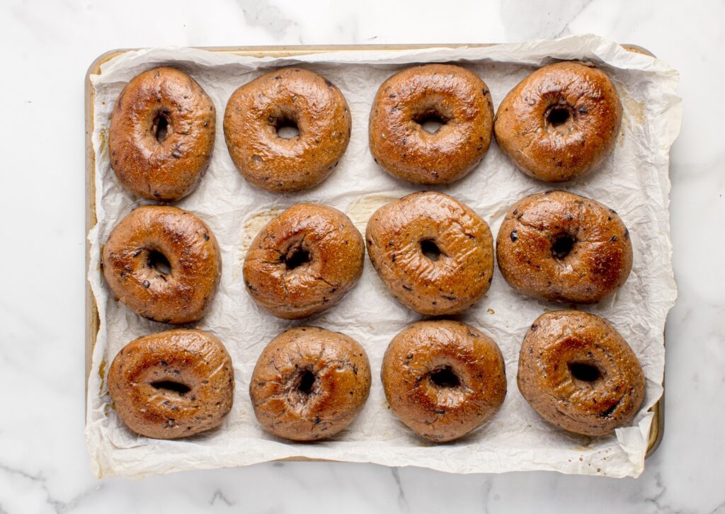 freshly baked sourdough blueberry bagels on baking tray
