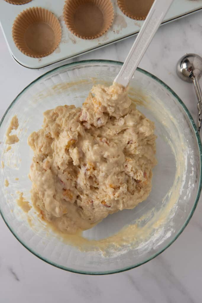 mixing bowl with batter for sourdough muffins next to muffin pan