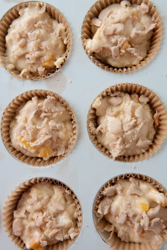 muffin pan filled with muffin batter and topped with crumble
