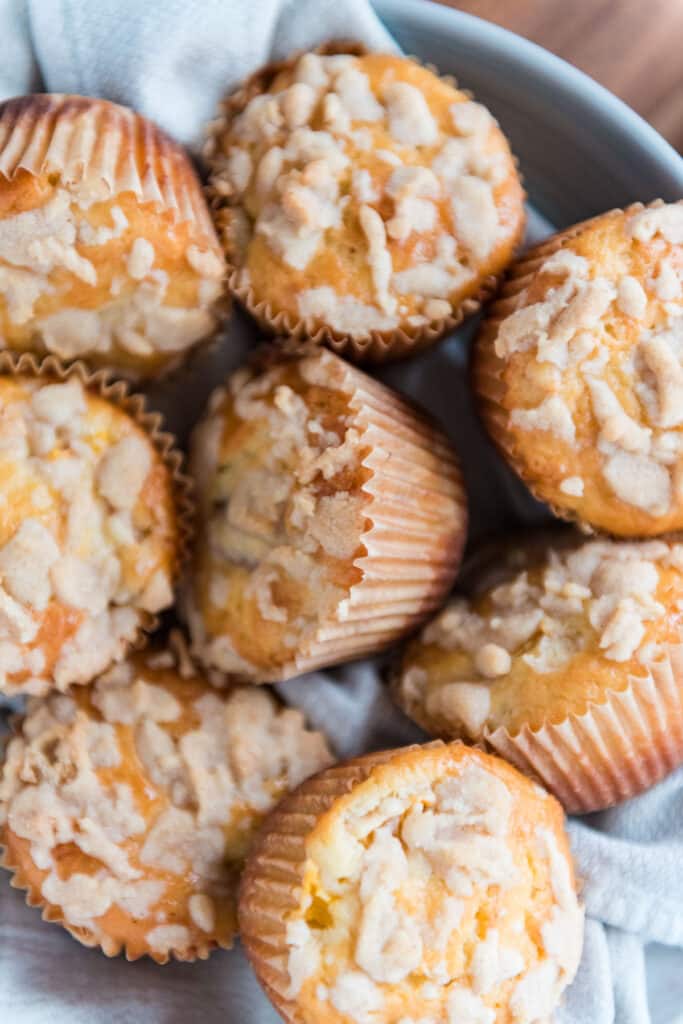 closeup image of sourdough peach muffins in a bowl showing crumb topping