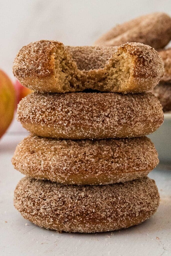 stack of four sourdough apple cider donuts with a bite taken out of the top donut.