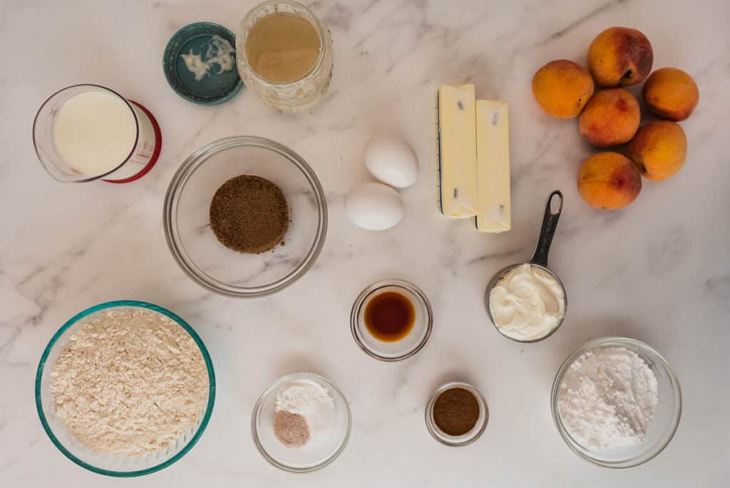 ingredients for sourdough peach coffee cake in glass bowls on marble counter