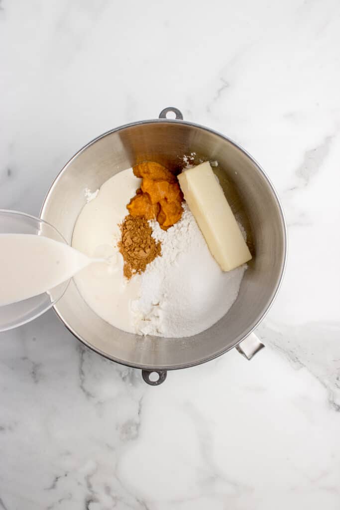 metal mixing bowl with ingredients being added for cinnamon rolls