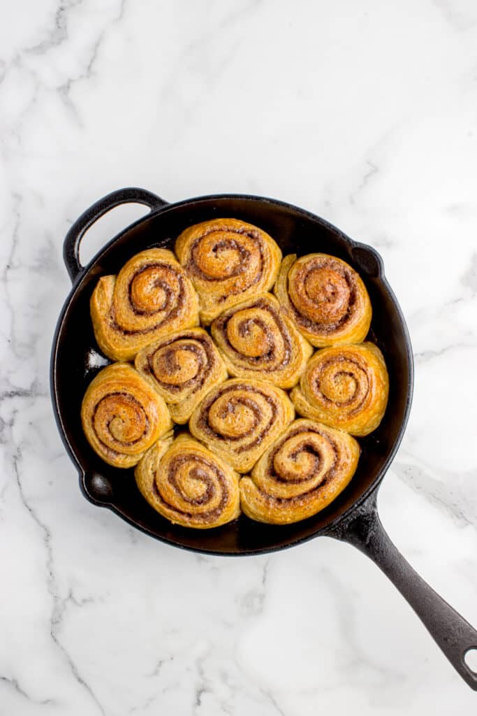 cast iron skillet with sourdough pumpkin cinnamon rolls after baking
