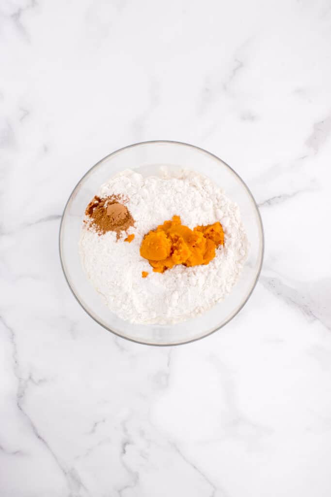 glass mixing bowl with ingredients for pumpkin dinner rolls
