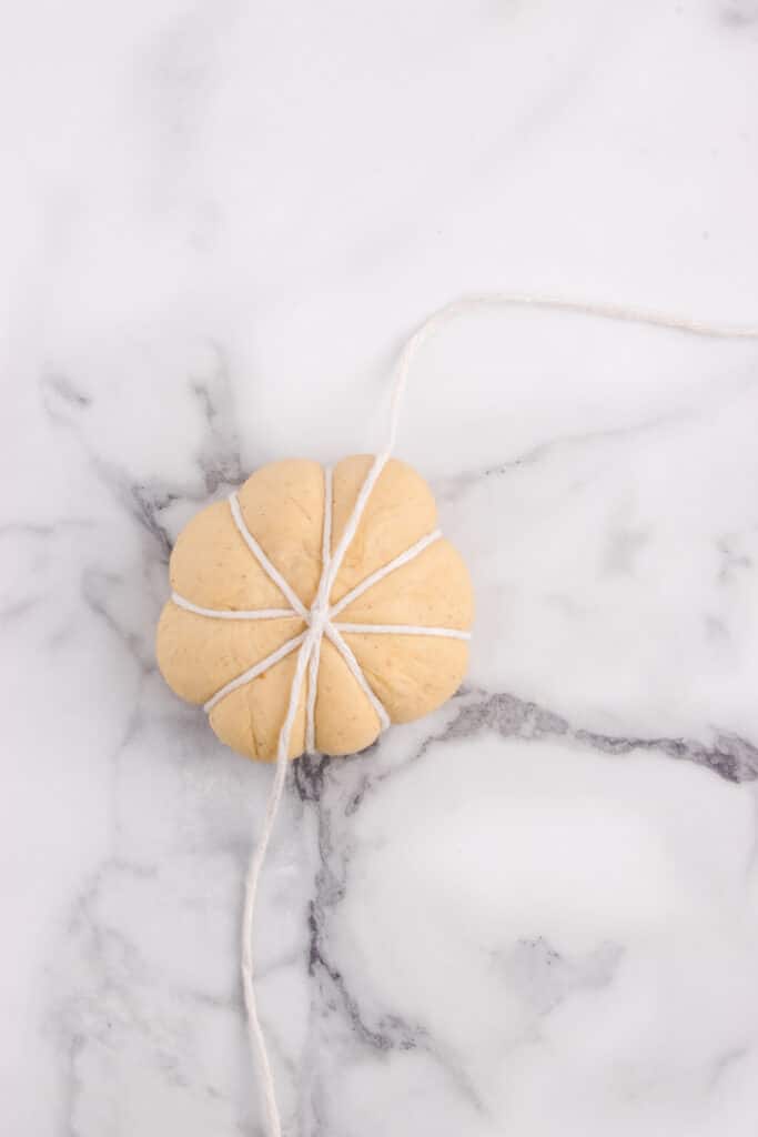 kitchen string wrapped around ball of dough to form pumpkin shape