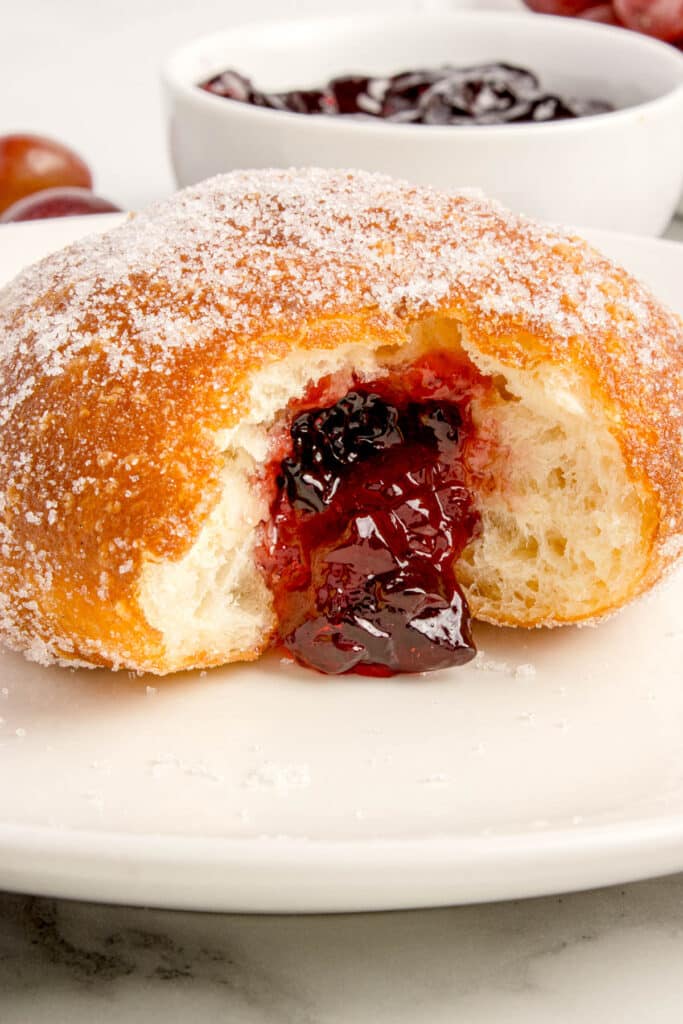closeup of sourdough donut stuffed with jelly with bite taken out