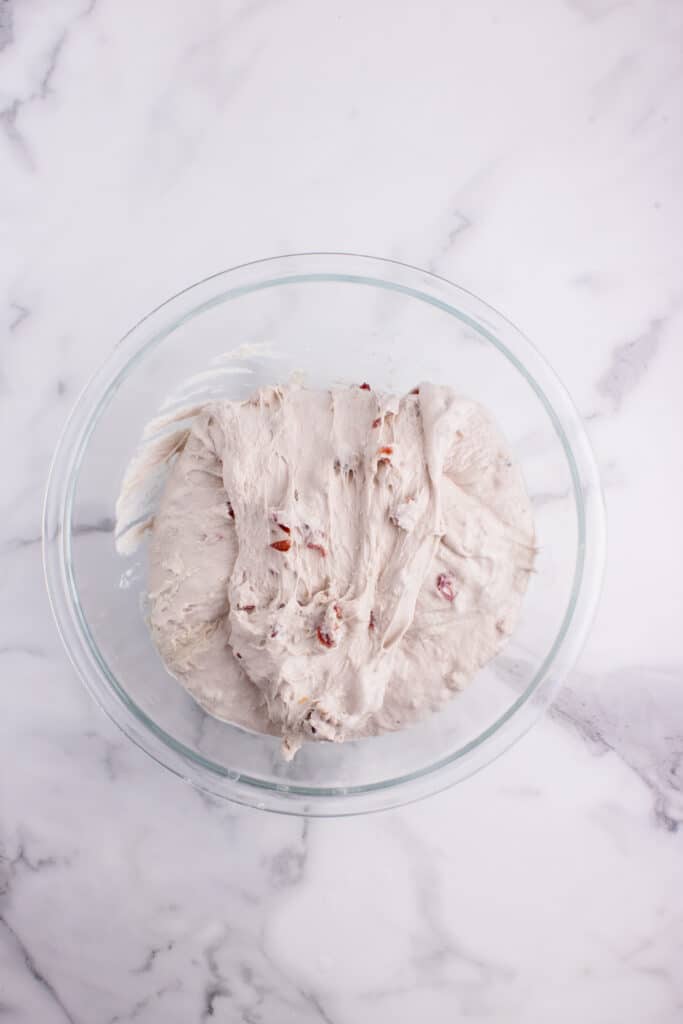 glass bowl with sourdough bread dough with cranberries and walnuts after set of stretch and folds