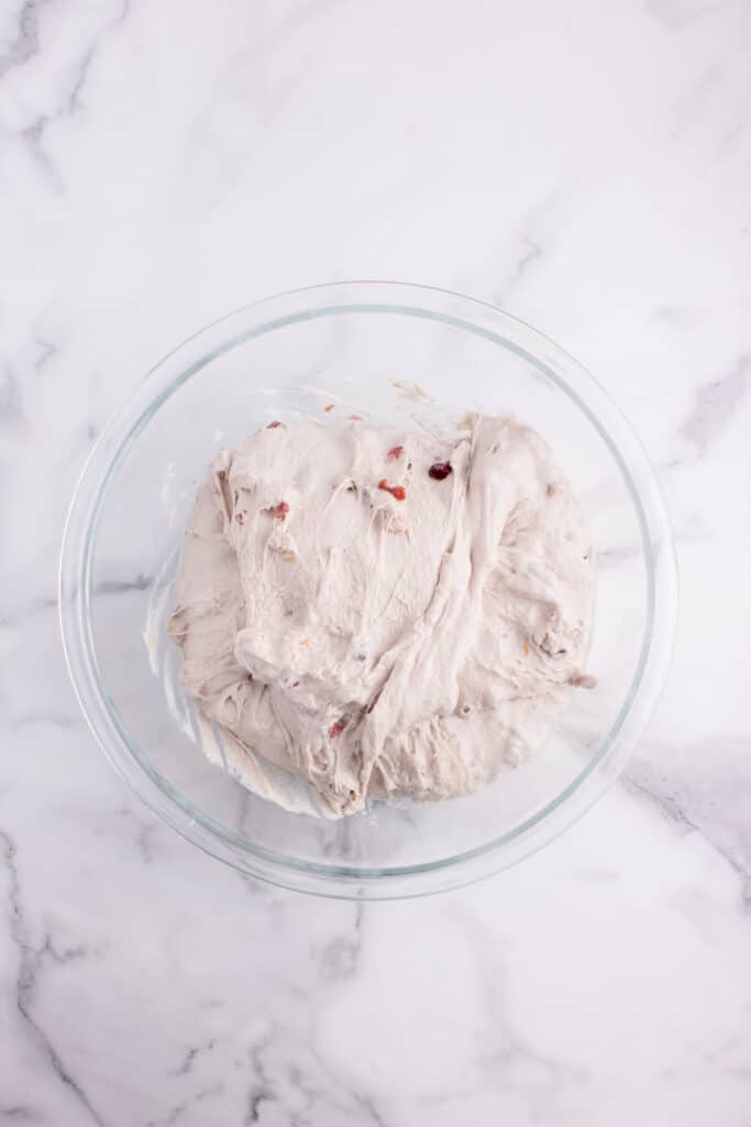 glass bowl with sourdough bread dough with cranberries and walnuts after set of stretch and folds