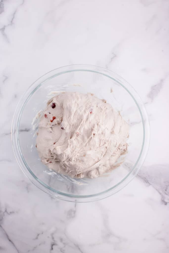 sourdough bread dough with cranberries and walnuts in glass bowl ready for bulk ferment