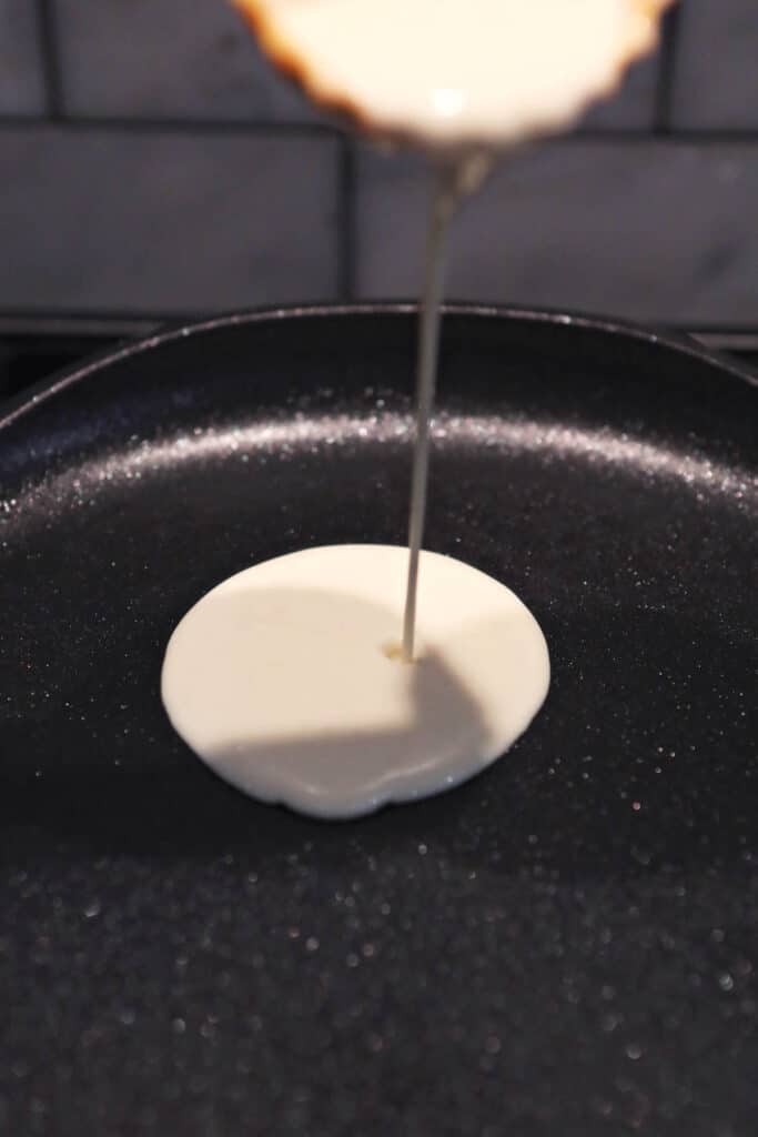 pouring sourdough crepe batter onto skillet