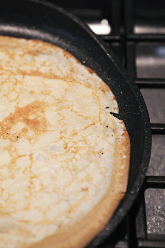 skillet with cooked sourdough crepe showing doneness