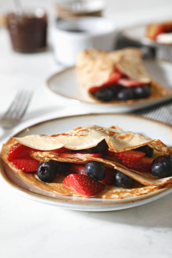 two plates with sourdough crepes filled with fresh berries