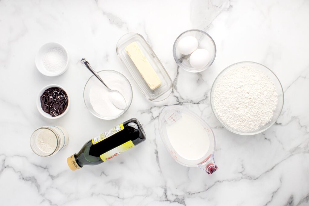 ingredients for sourdough jelly filled donuts in glass bowls on marble counter