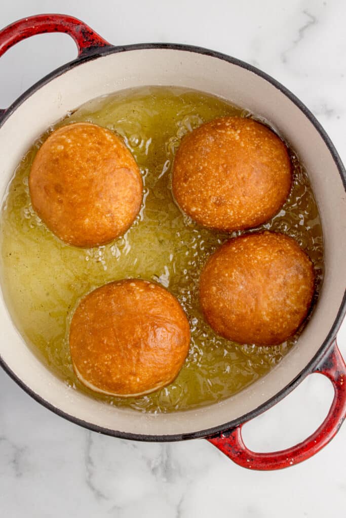 four sourdough donuts being fried in oil