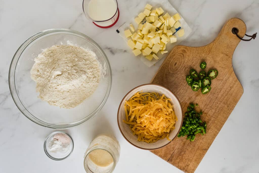 ingredients for sourdough cheddar jalapeno biscuits on marble counter