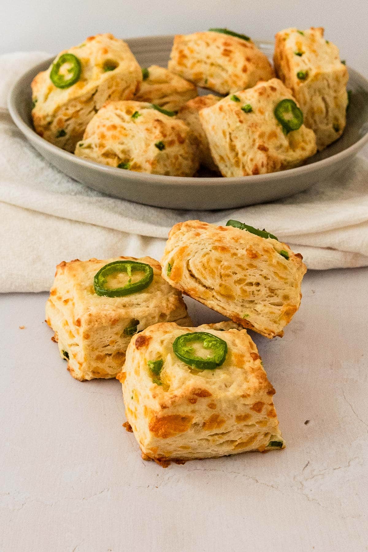 three sourdough discard jalapeño biscuits on counter with bowl of more in background