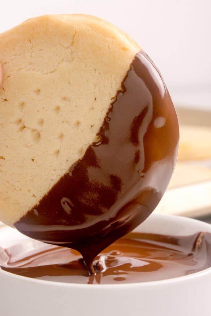 shortbread cookie being dipped into melted chocolate