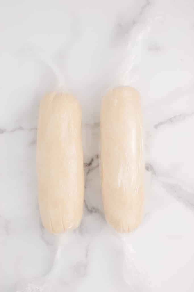two logs of shortbread dough wrapped in plastic wrap